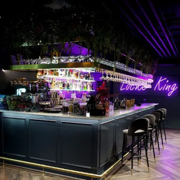 Bar area with a neon 'Locke King' sign and shelves of glassware