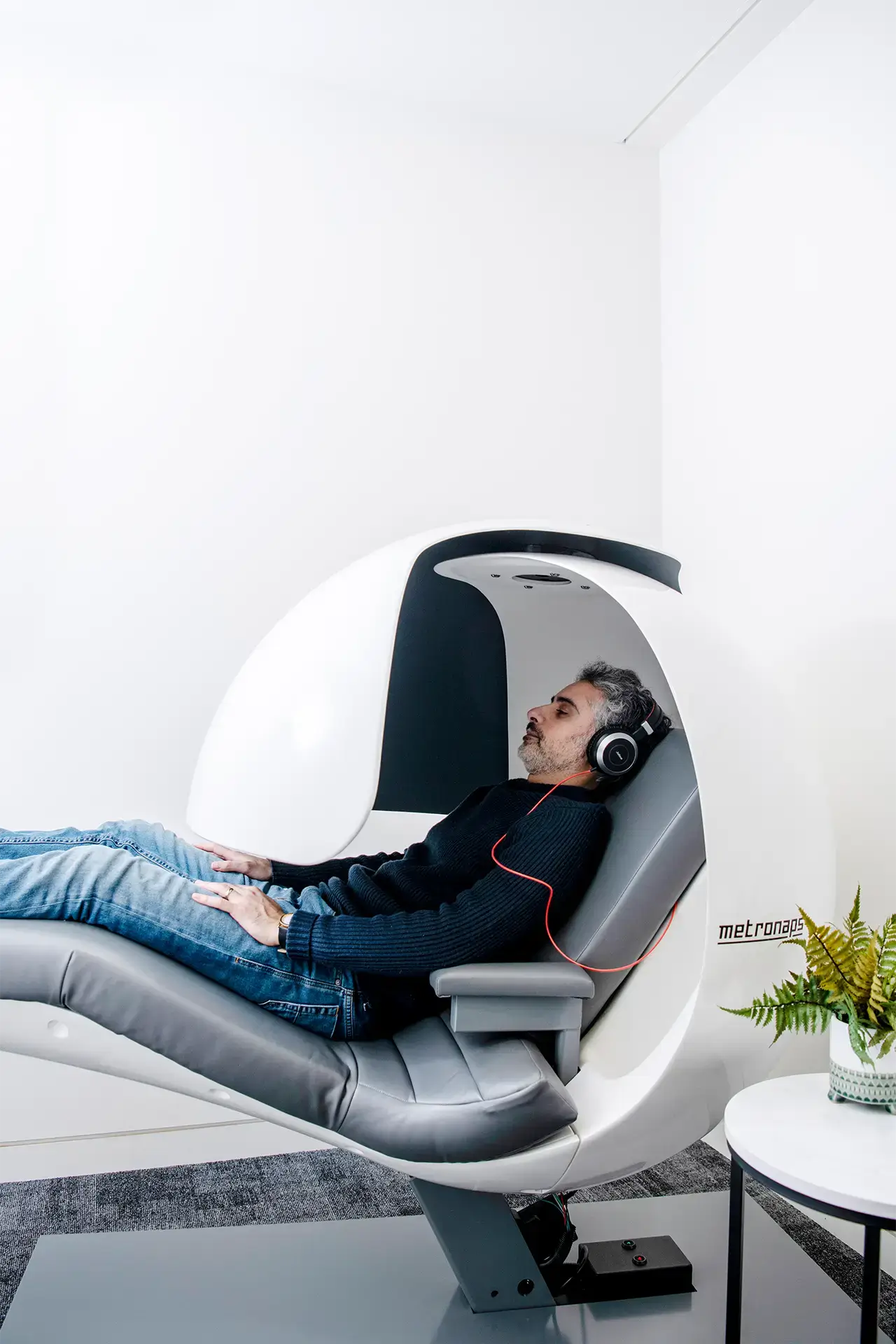 Man relaxing with headphones in a MetroNaps sleep pod
