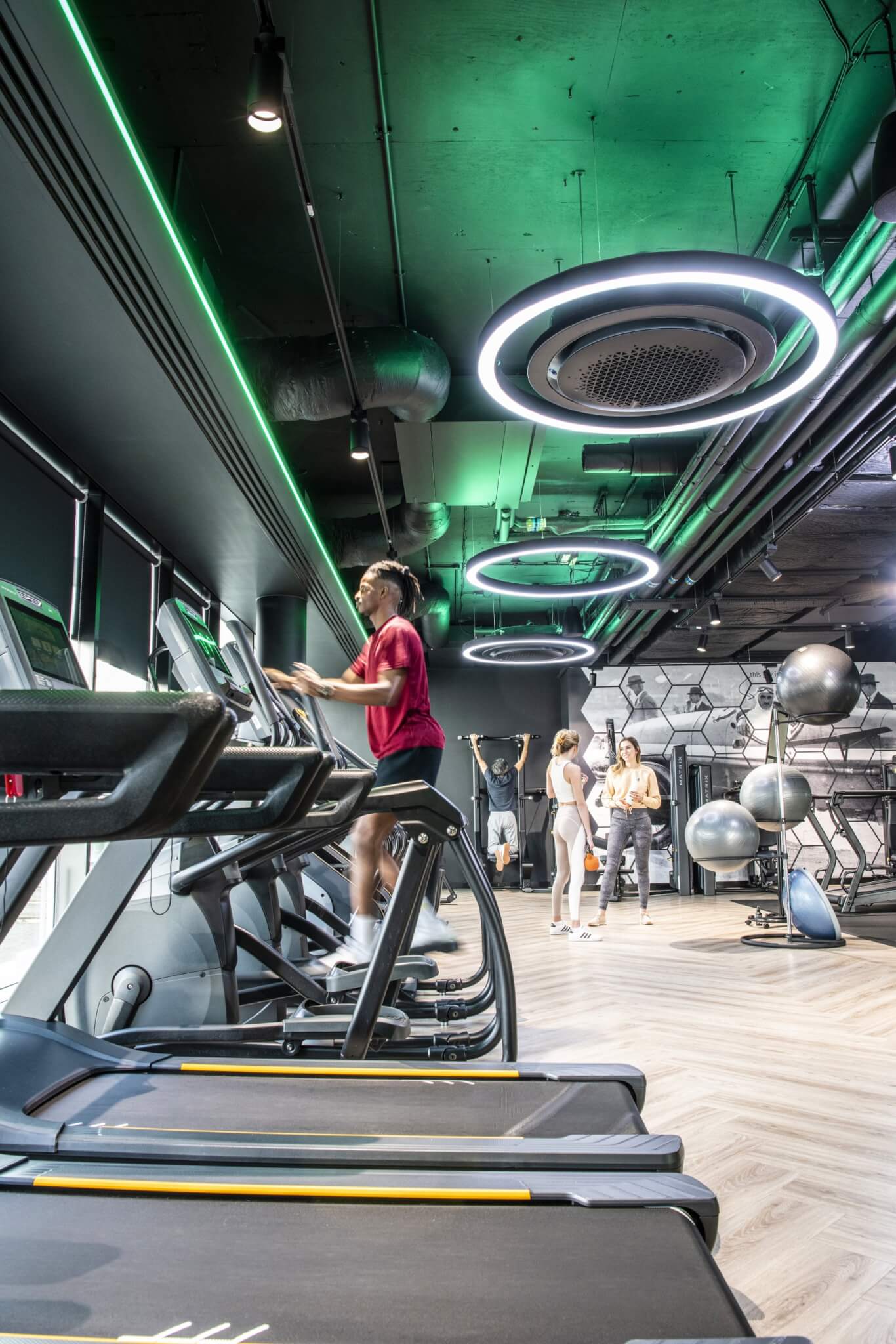 Gym floor with treadmills, exercise equipment and green ambient lighting