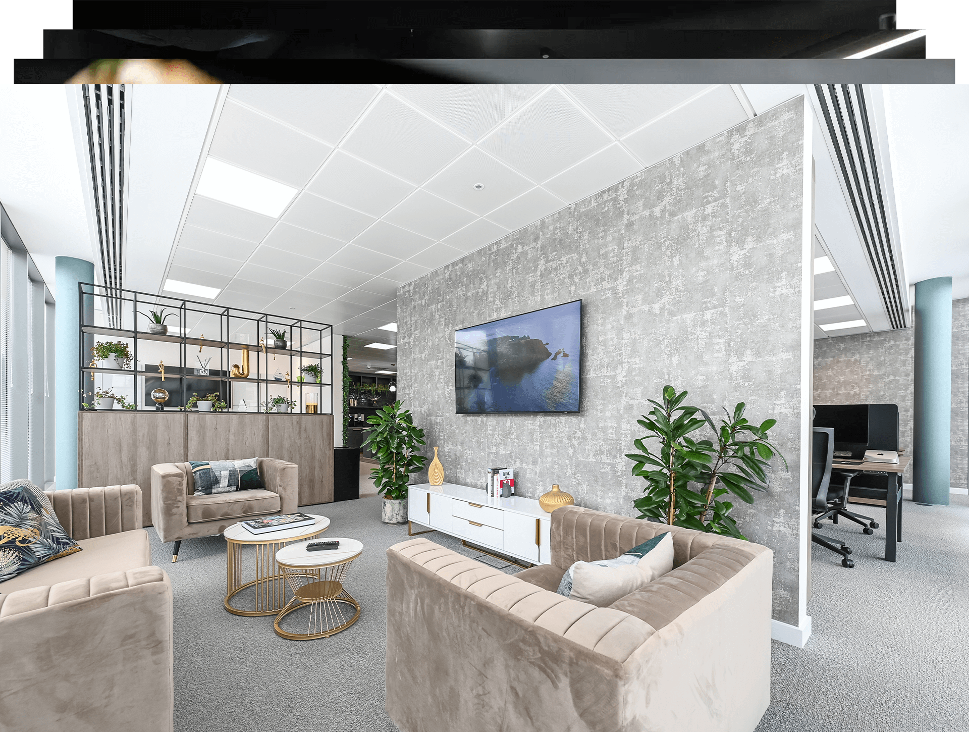 Stylish office breakout lounge with velvet sofas, a wall-mounted TV and workstations