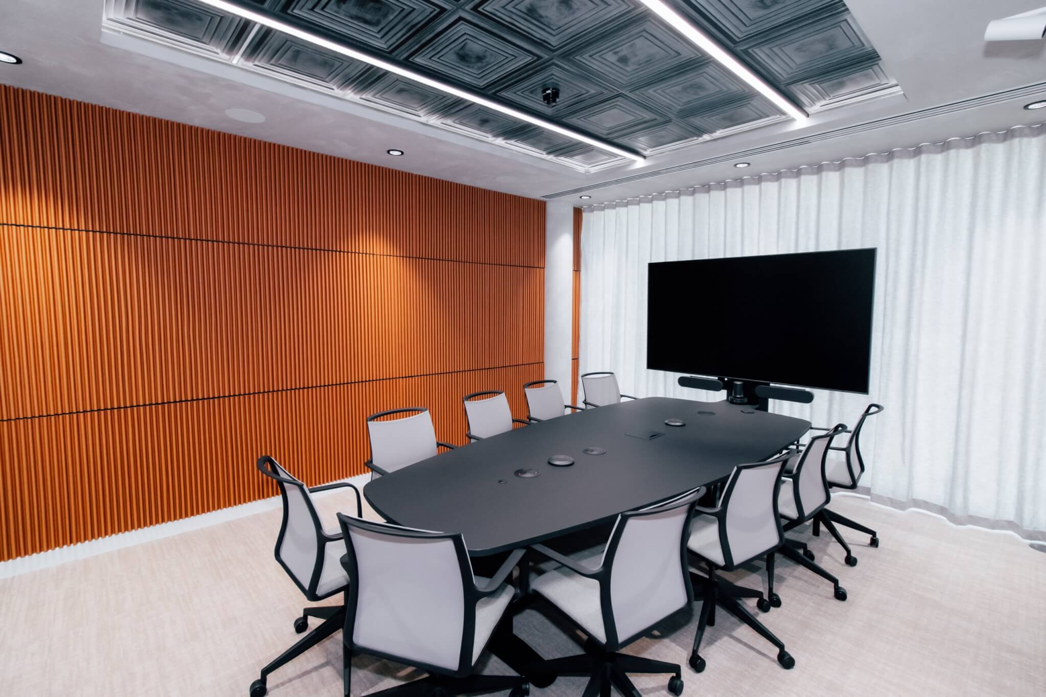 Meeting room with an orange slatted wood feature wall and a large display screen
