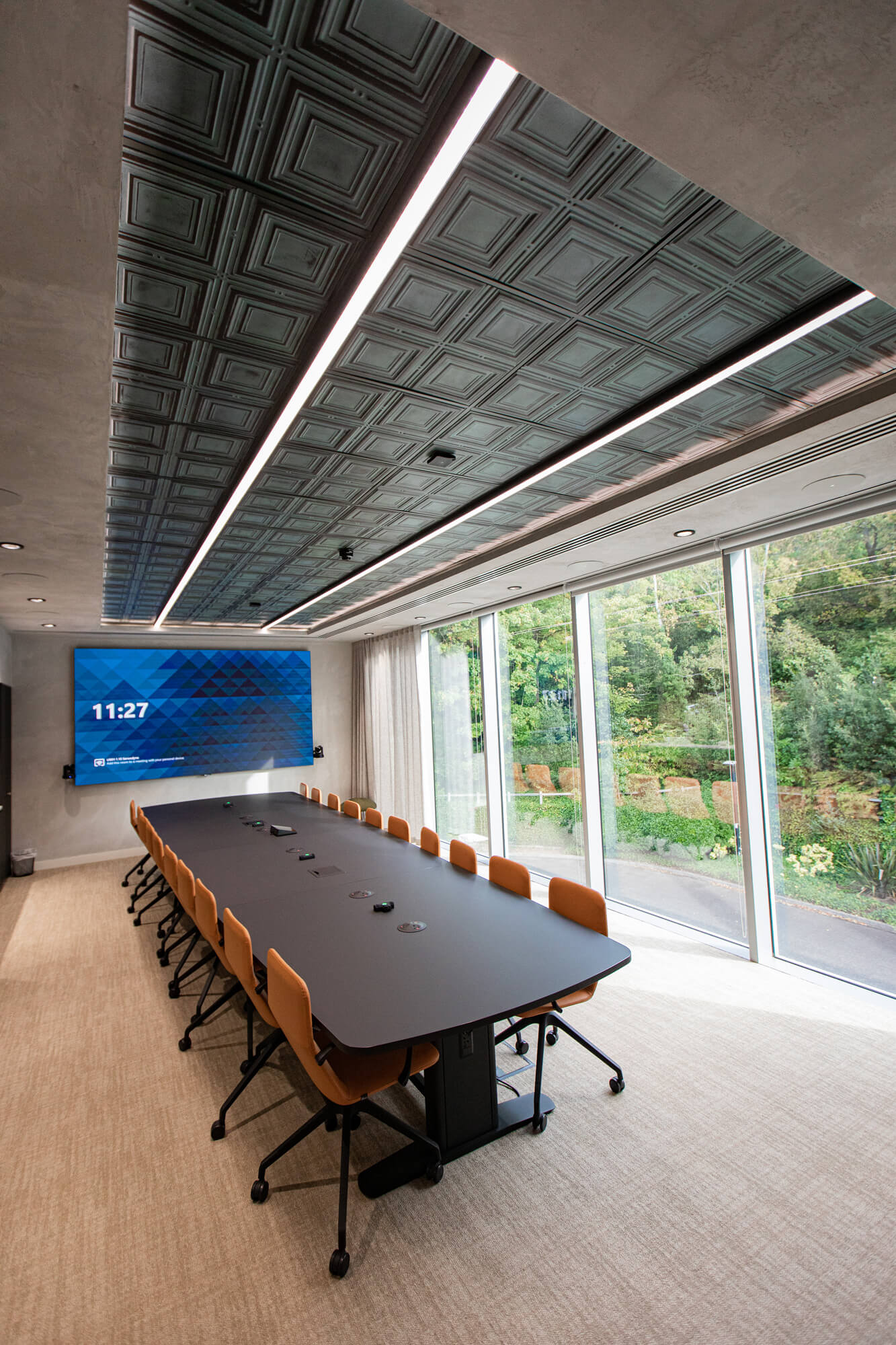 Meeting room with a digital clock display and floor-to-ceiling windows overlooking greenery