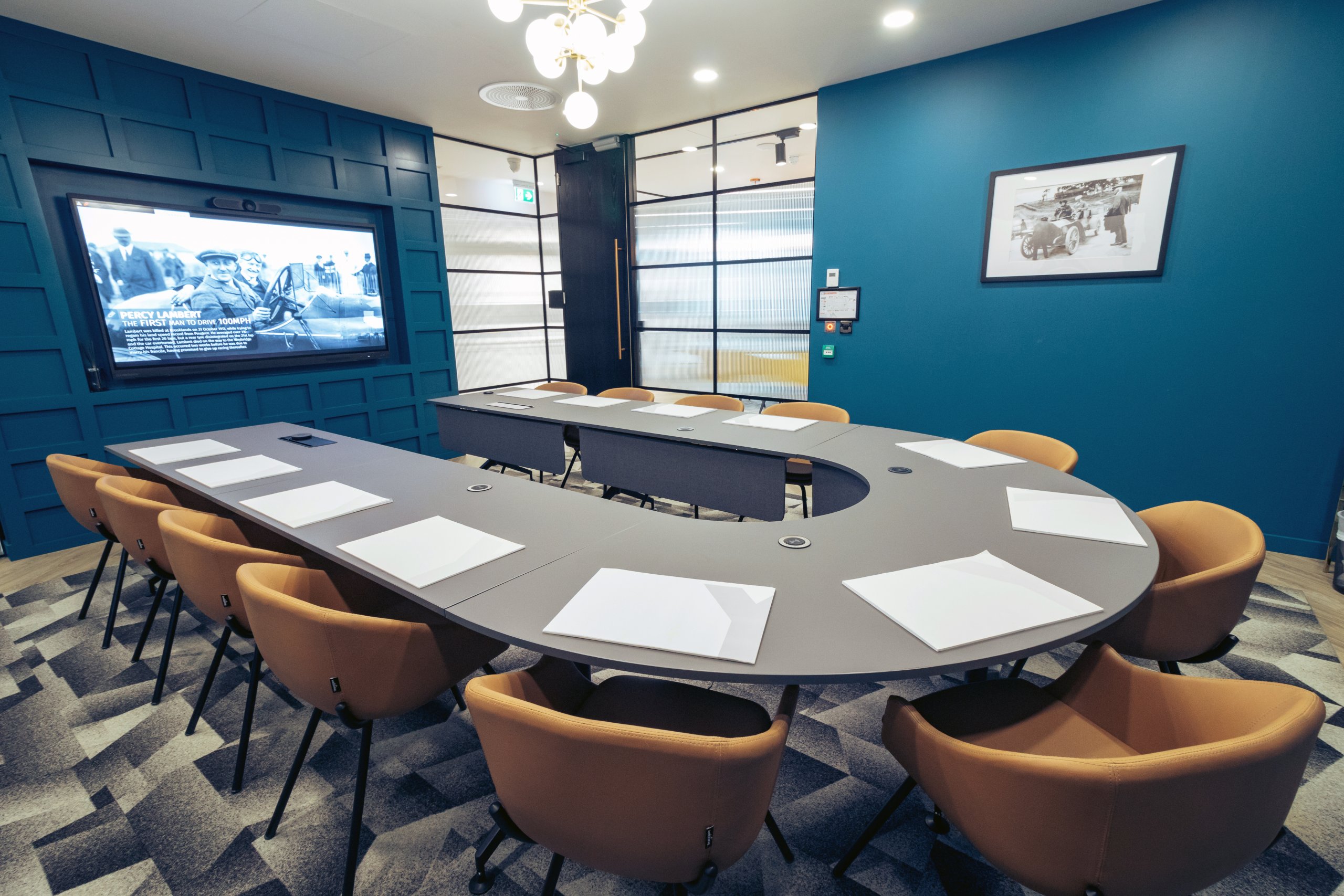 The Lambert Suite meeting room with a screen displaying Percy Lambert's racing history and teal panelled walls