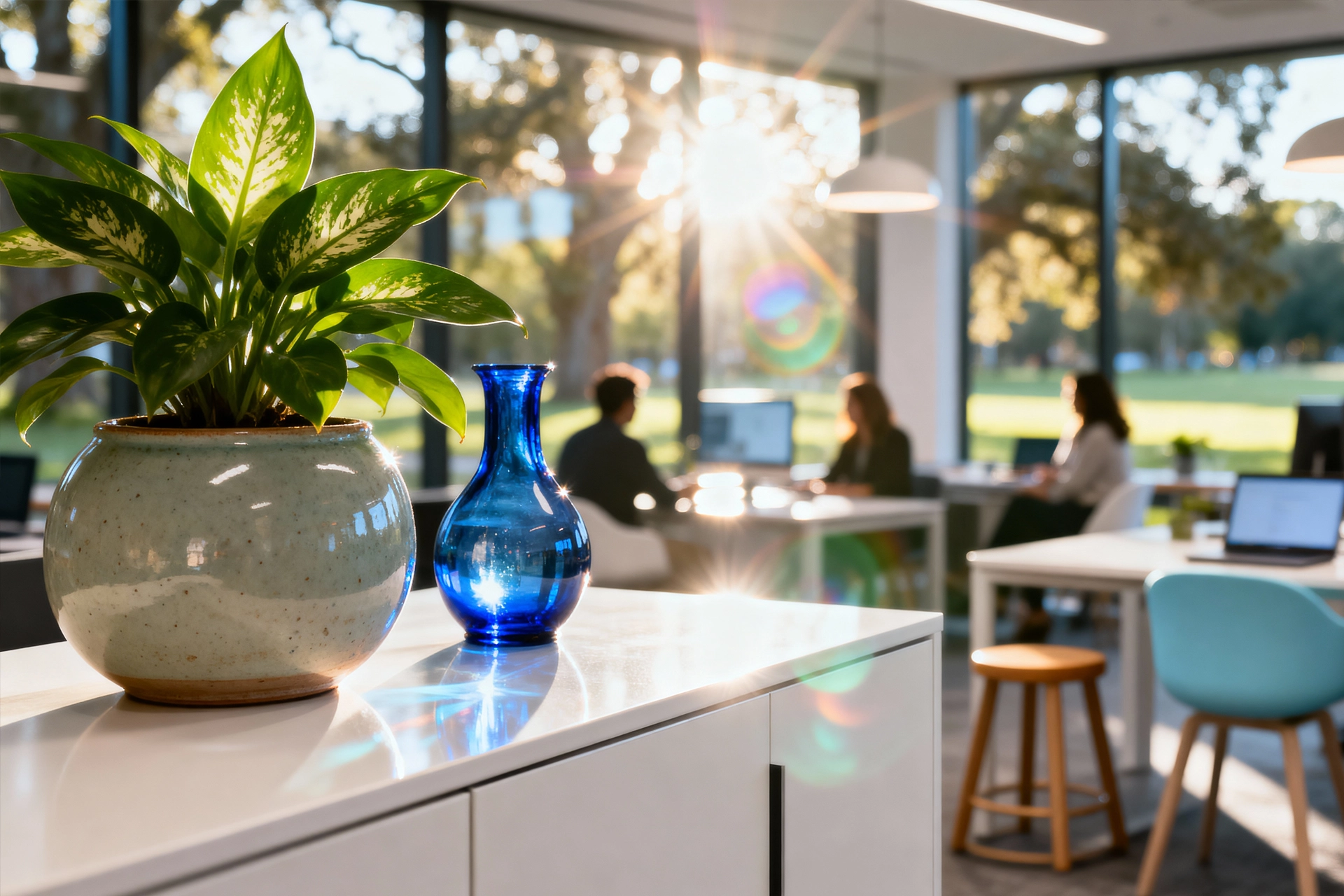 Potted plant and blue glass vase on a white counter with a coworking office in the background