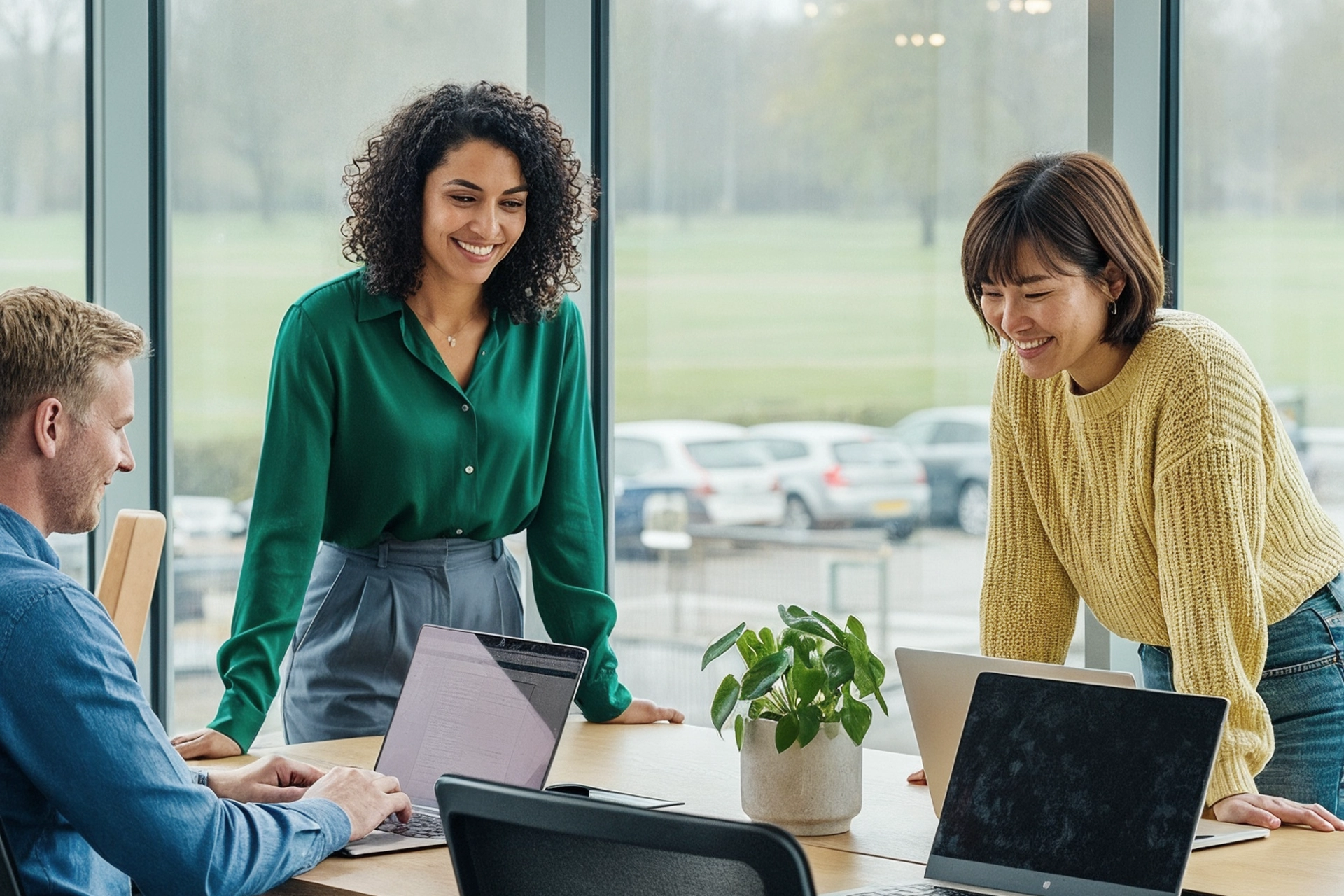 Three colleagues smiling together while working on laptops